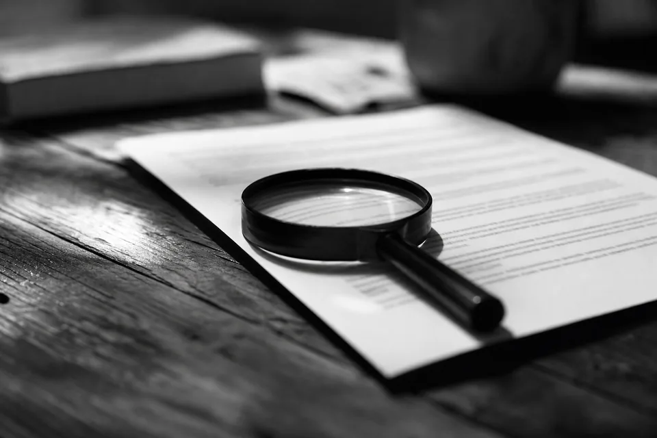 Magnifying glass lying on a printed page on a wooden desk